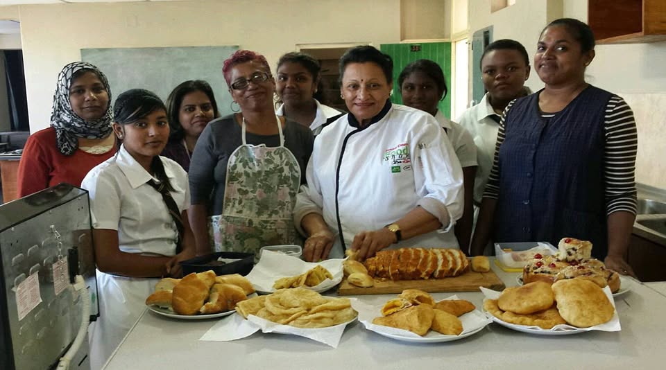 Participants in a baking session with a visiting chef, showing fresh bread and pastries on the counter